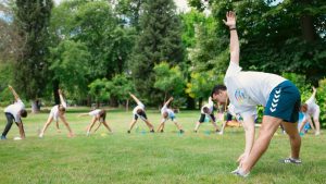 Kids stretching exercises in a park guided by a coach, promoting fitness and fun.